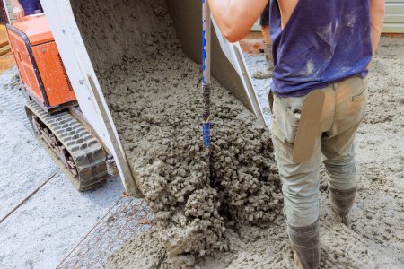 Beim Bau von Fundamenten wird nasser frischer Zement aus Betonbuggy in das Gerüst im Boden gegossen