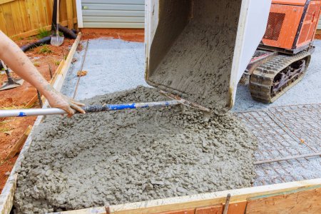 Self dumping track concrete buggy is used to pour wet cement into framework during foundation construction