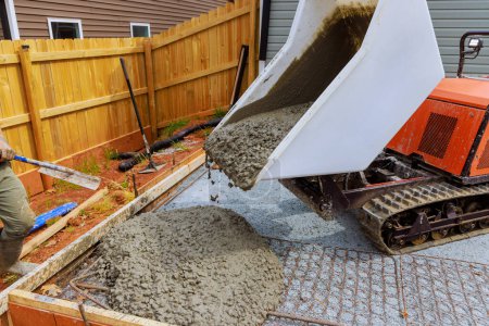 Téléchargez les photos : Construction de fondations implique le versement de ciment humide dans le cadre en utilisant la voie d'auto-déversement buggy béton pendant la phase de construction - en image libre de droit