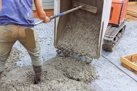 Verter cemento fresco de buggy de hormigón en el marco en el suelo durante la construcción