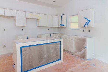 Cabinets are being installed in newly constructed house with wooden white cabinets