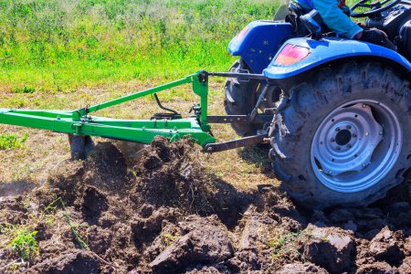 Traktor pflügt Feld um, um es für die Aussaat von Getreide im Frühjahr vorzubereiten