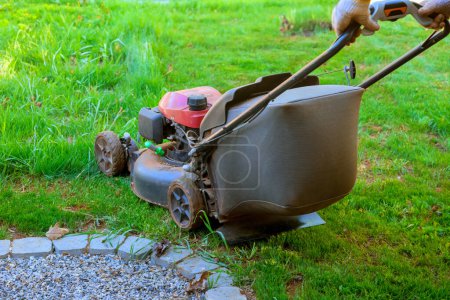 Lawn mower for trimming cutting lawns on green grass in backyard of his house