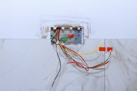 Electricista profesional que trabaja la conexión eléctrica del enchufe en la pared del sistema eléctrico en el hogar durante la renovación