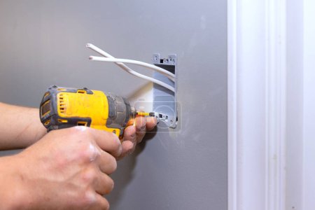 En el curso de la renovación de la residencia, electricista profesional conecta un enchufe eléctrico a la pared