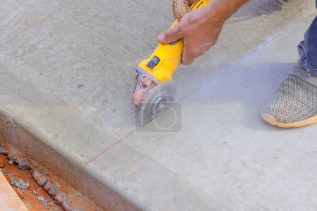 Bauarbeiter schneidet Betonfundamente mit Schleifmaschine nach dem Gießen