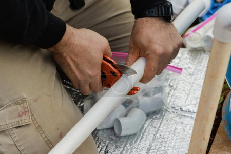 Klempner schneidet Kunststoff-PVC-Rohr mit spezieller Schere