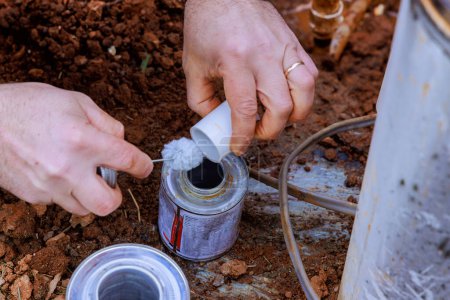 Klempner verwenden klare Grundierung für PVC-Rohre, bevor sie sie vor Abschluss der Reparaturarbeiten verkleben