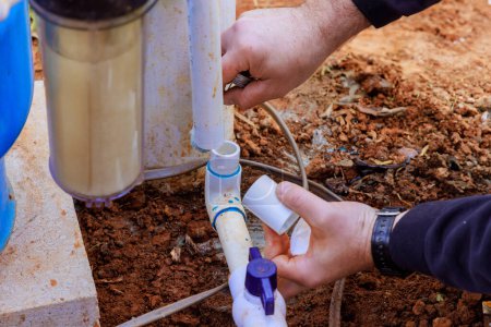 Photo for As part of repair work, technician plumber uses clear primer for PVC pipe with before gluing pipes - Royalty Free Image
