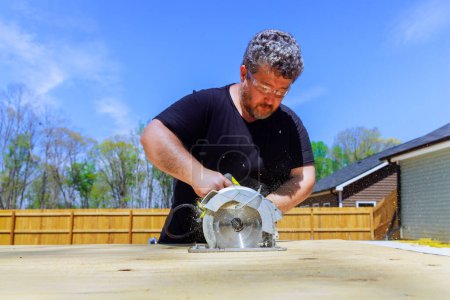 Using handsaw, carpenter trims plywood boards