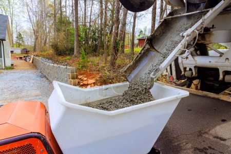 Baustelle zeigt nassen Zement, der aus Zement-LKW-Rutsche in Beton-Buggy mit Schubkarre fährt