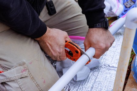 During repair work, technician plumber uses special scissors to cut PVC pipe made of plastic