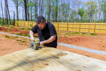 Carpintero profesional en el corte de madera contrachapada utilizando sierra de mano circular eléctrica
