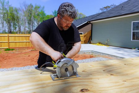 Carpenter uses hand saw to trim plywood boards
