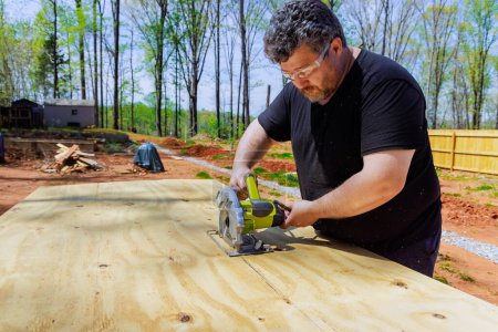 Carpenter trims plywood boards using hand saw