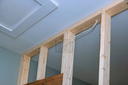 Téléchargez les photos : Sur le site de rénovation de la maison, des vis à cloison sèche sont utilisées pour monter des plaques de plâtre sur des poutres en bois - en image libre de droit