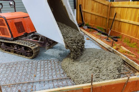 Wet cement is poured into framework during foundation construction using self dumping track concrete buggy