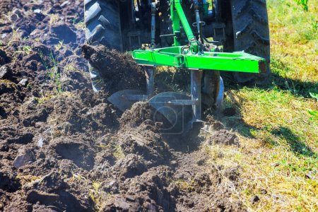 En primavera, los arados del tractor se utilizan para cultivar el suelo y preparar el campo para sembrar grano