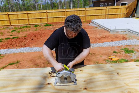 Carpenter trims plywood boards with handsaw