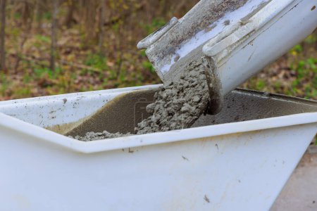 Betonbuggy auf Baustelle wird mit nassem Zement aus Zement-LKW-Rutsche beladen