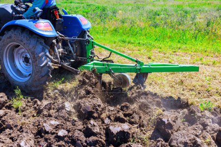 During spring, tractor ploughs field, cultivates soil, prepares it for sowing grain