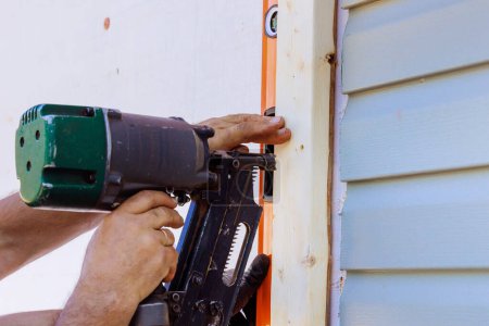 Foto de Trabajador instalando vigas usando un martillo de aire en marco de madera - Imagen libre de derechos