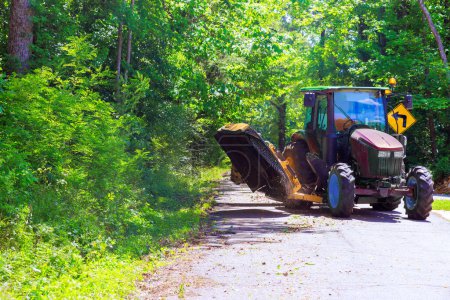 Cutting grass branches on both sides of road with municipal service tractor mower