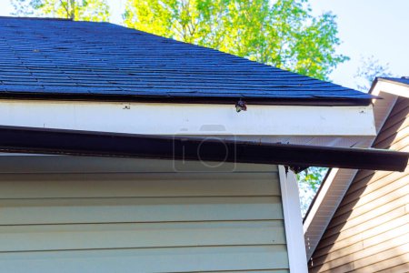 Photo for Broken rain gutter on roof of house after hurricane damages - Royalty Free Image
