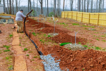 Installation d'un tuyau de drainage pluvial dans le drain de tranchée pour drainer l'eau de pluie