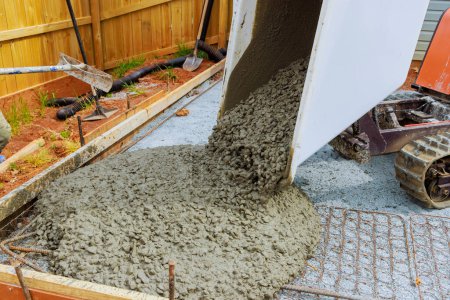 Téléchargez les photos : Au cours de la construction de la fondation, le ciment humide est versé dans le cadre du buggy en béton équipé d'une voie d'auto-vidange - en image libre de droit