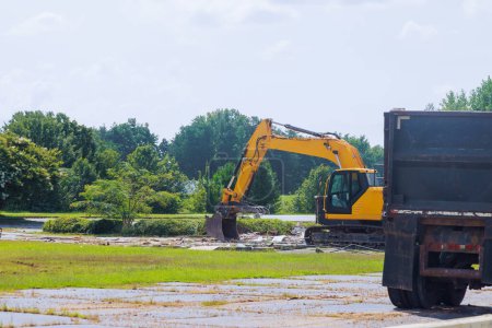 At construction site, an excavator loads concrete waste into dump container