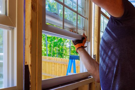 An installation of plastic windows in new home is performed by construction worker