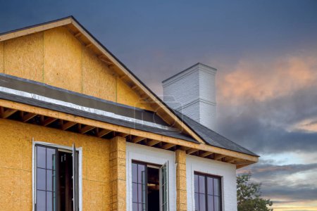 Foto de Una casa en construcción tiene marco de viga características de madera contrachapada, soportes de canalón, ajuste fascia soffit instalado - Imagen libre de derechos