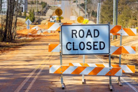 Señal que indica que la carretera está cerrada con franjas anaranjadas cerca del sitio de construcción que impide que los vehículos conduzcan
