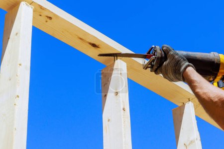 Foto de Trabajar con sierra alternativa en el tema de la construcción es una herramienta eléctrica para cortar vigas de madera - Imagen libre de derechos
