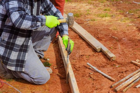 Bauarbeiter fertigen Vorlagen mit herausnehmbaren Holzschalungen zum Betonieren von Fundamenten