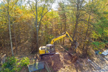 Photo for Preparation of land for construction, use of an excavator tractor to uproot trees make space for construction of house - Royalty Free Image
