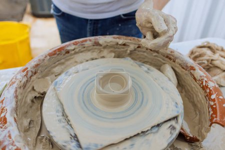 Creating clay dishes on potter wheel, a potter hand sculpts soft clay with wet hands