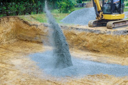 An excavator is to fill irregularities in excavations with granite rubble base in order to serve as foundation for concrete pours