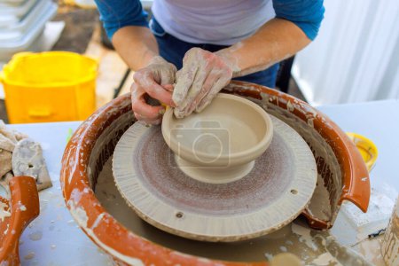En la rueda de alfarero, alfarero formas de arcilla suave con las manos mojadas para elaborar platos de arcilla