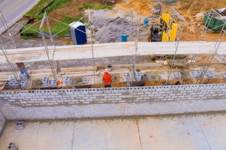 Téléchargez les photos : Bâtiment mur de béton de travail avec des blocs de béton sur échafaudage par maçon - en image libre de droit