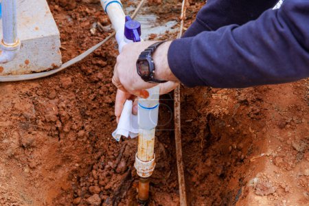 Plumber glues pipes to connect water to house