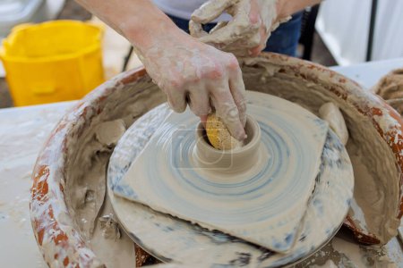 Professional potter worker creating bowl with wet soft clay using potter wheel