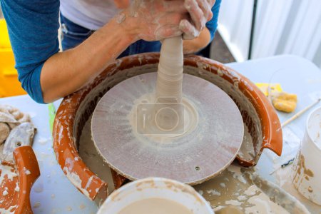 Working with wet soft clay on potters wheel, potter creates bowl