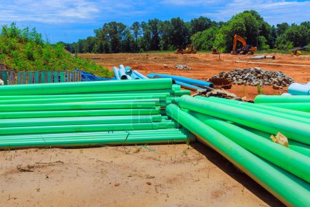 On construction site there are green PVC pipes used to lay pipe water system for new house