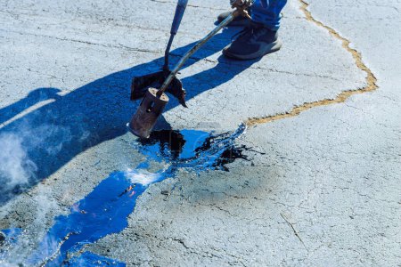 Joint seal restorers at parking lots heat cracks in asphalt before they are filled with hot bitumen emulsion