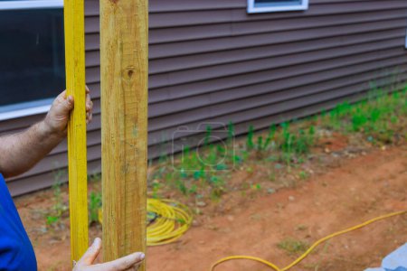 Building wooden fence in backyard checking posts with level