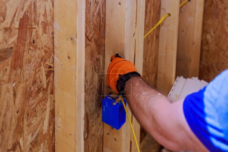 Un électricien installe des fils électriques sur place pendant la construction d'un bâtiment résidentiel