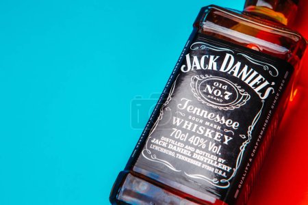 Foto de Khmelnytskyi, Ucrania - 22 de noviembre de 2022: Botella de vidrio del nuevo whisky de Tennessee Jack Daniel 's, Jack Daniel Distillery sobre fondo rojo y azul, espacio para copiar. Alcohol más vendido - Imagen libre de derechos