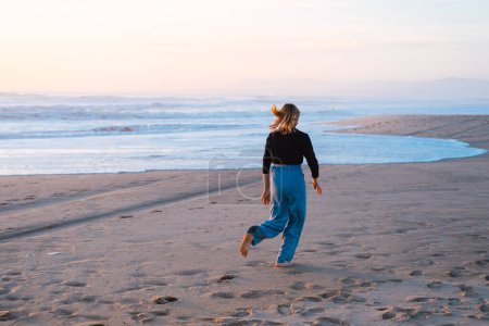Photo for Beautiful photo from behind of women. She walks near the ocean in Portugal. - Royalty Free Image